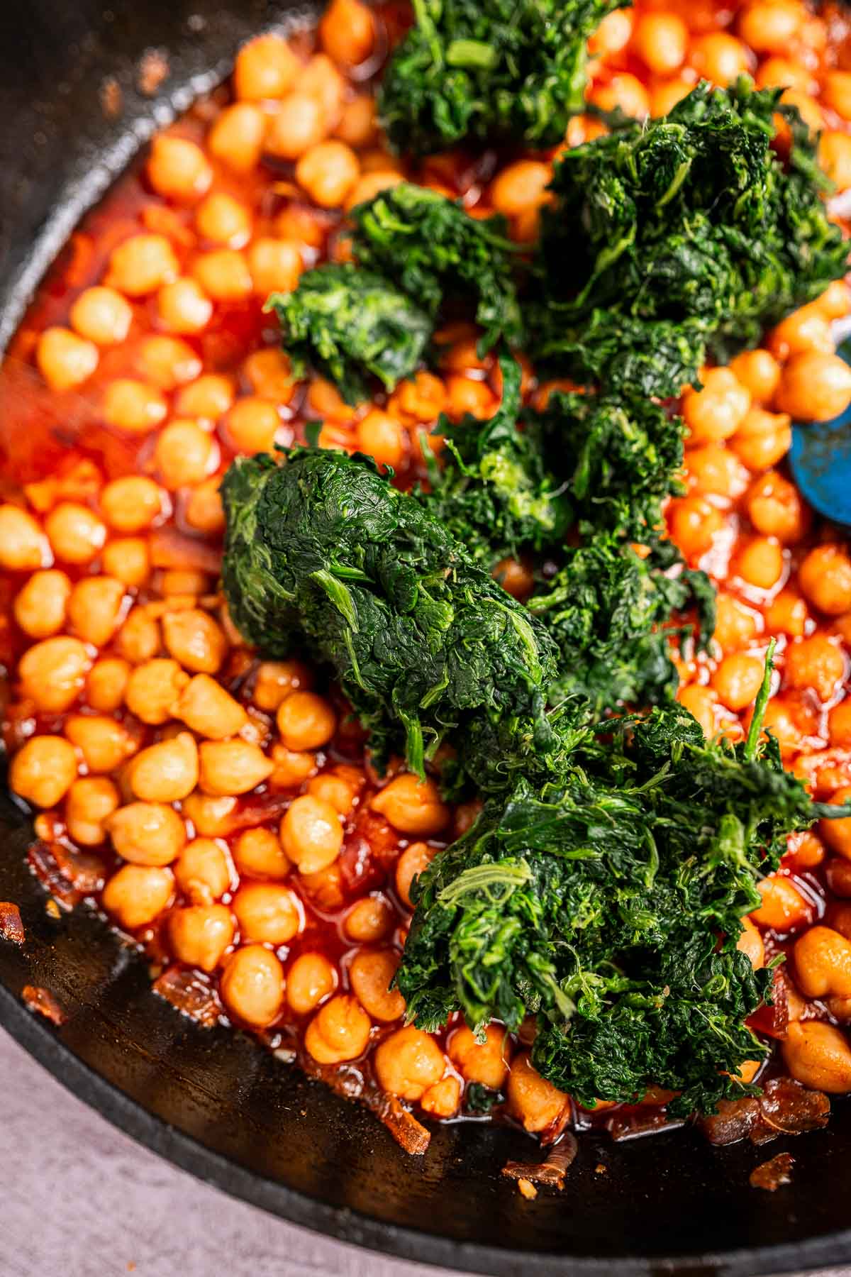 A delicious blend of spinach and chickpeas simmers in a skillet with a rich red sauce, creating the perfect harmony of flavors.