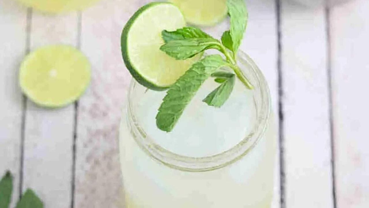 Ginger beer mocktail in a mason jar with fresh mint and lime on the jar and ingredients and another jar around it.