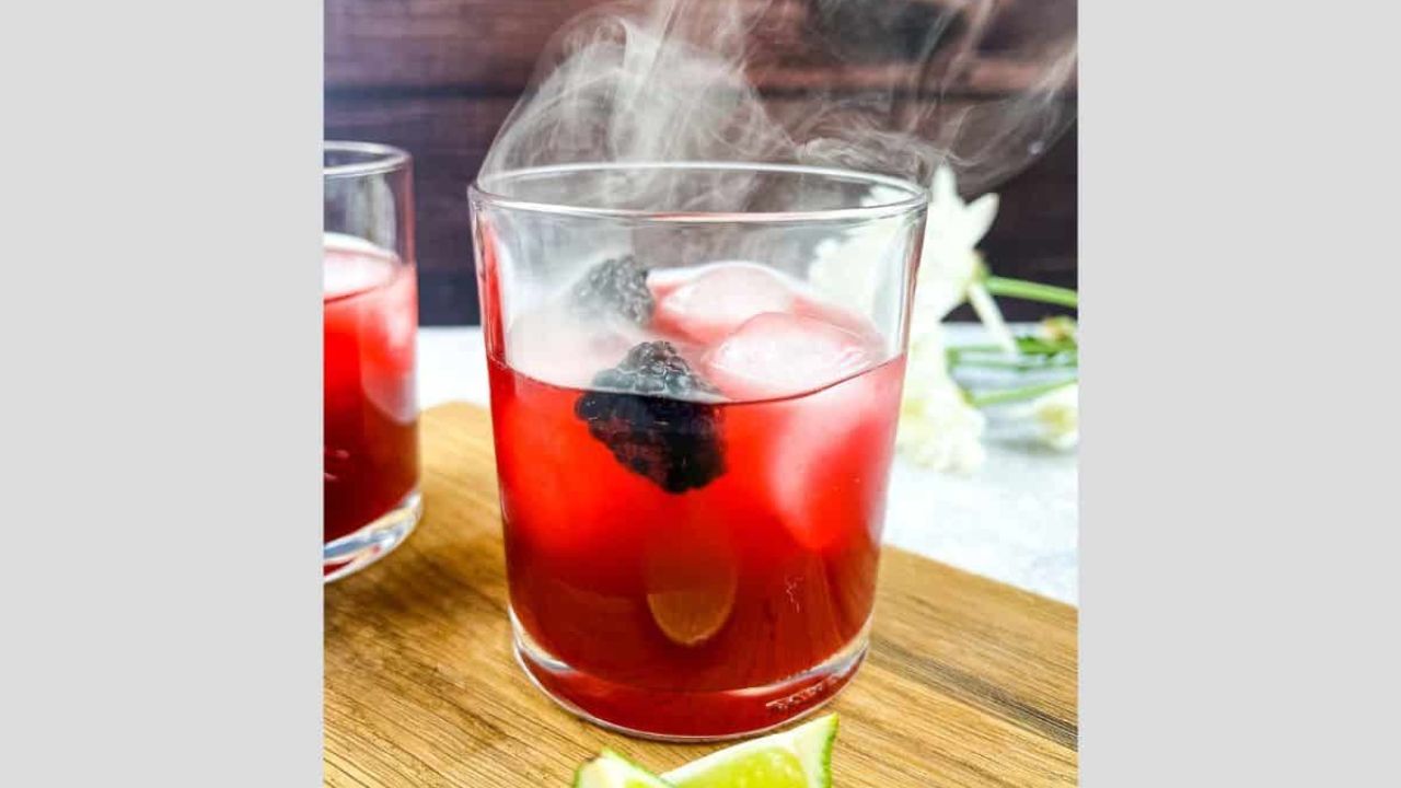 Smoked Blackberry Margarita with smoke coming out the top of the glass.