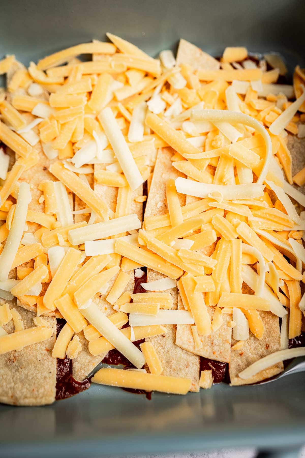 A delightful cheese enchiladas casserole featuring shredded cheese gracefully melting over tortilla chips in a baking dish.