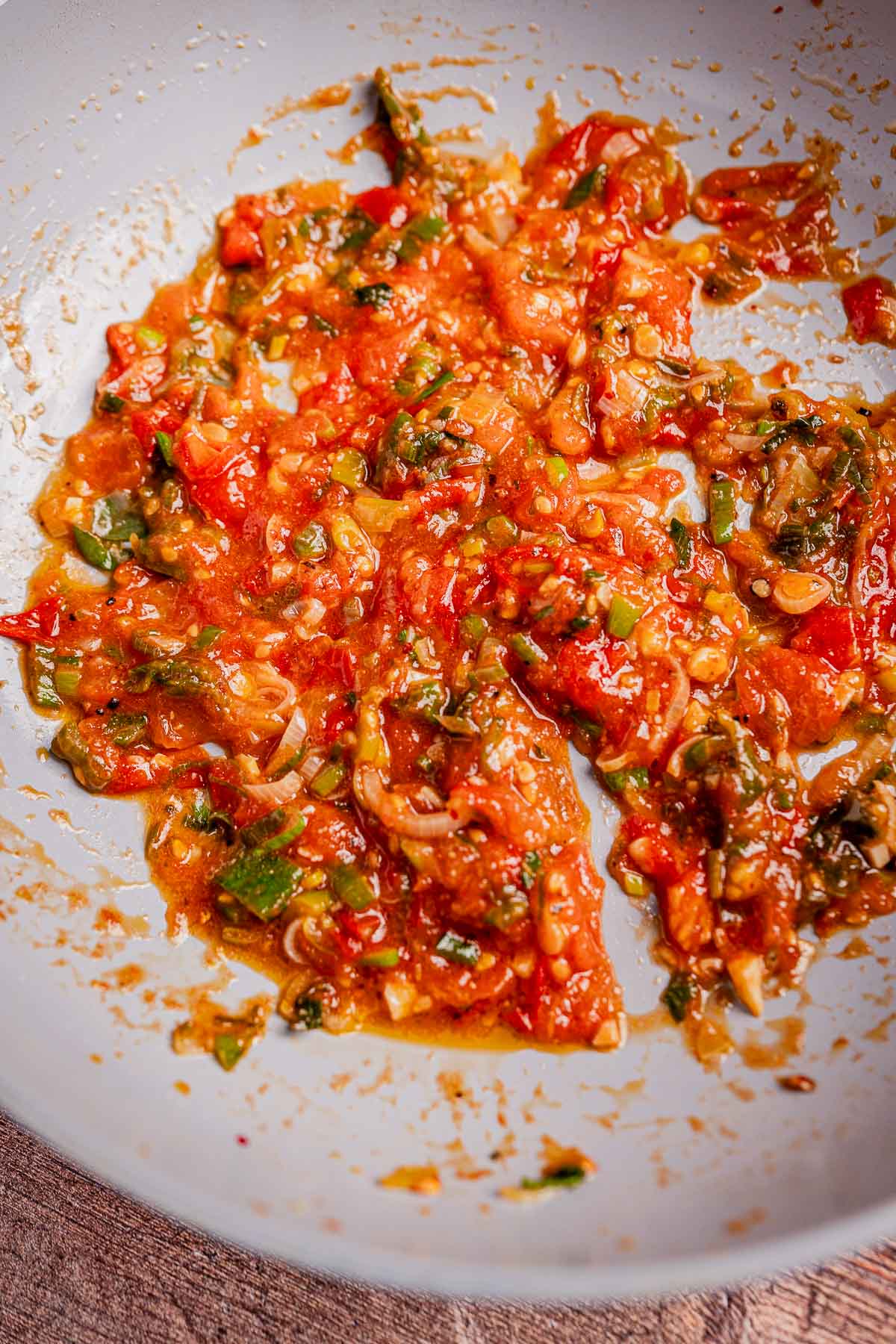 Close-up of a pan with a vibrant hogao, featuring cooked tomatoes, onions, and green peppers, forming a chunky, saucy texture.