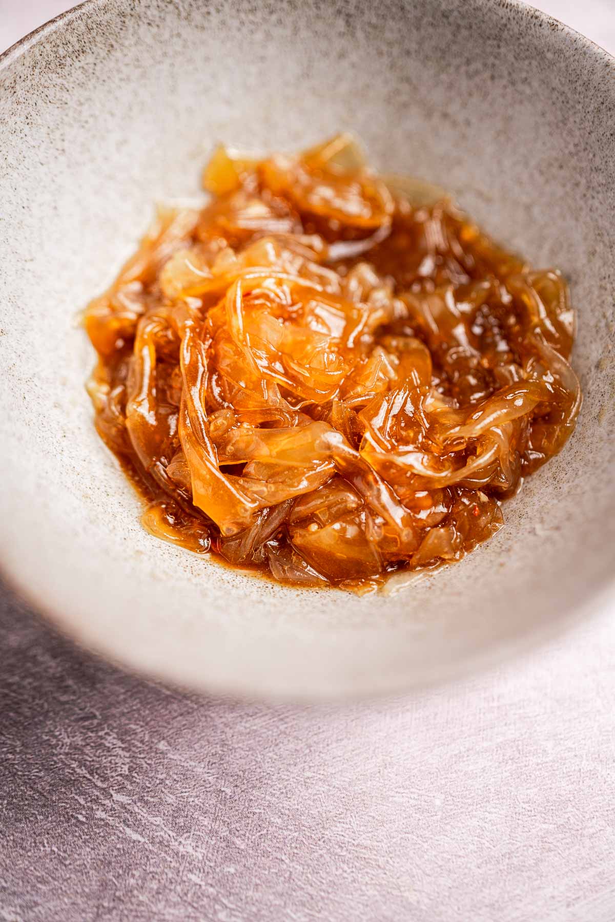 A bowl filled with caramelized onions nestles alongside delicate rice paper noodles.