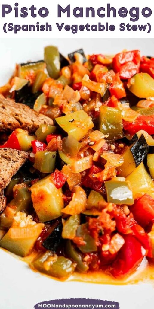 Close-up of a Spanish vegetable stew with zucchini, bell peppers, and tomatoes, garnished with bread slices. Text at the top reads, "Pisto Manchego (Spanish Vegetable Stew).