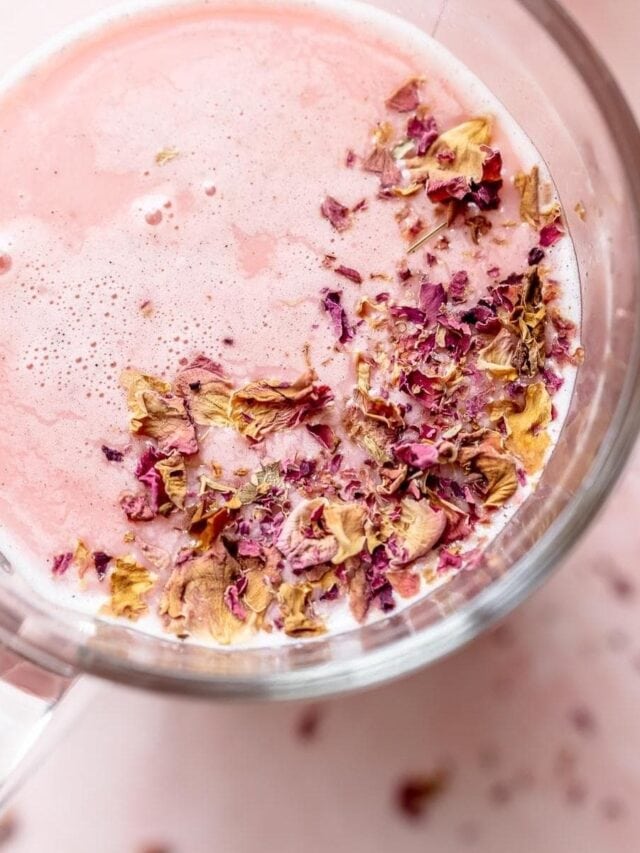 A glass cup filled with pink liquid, topped with dried rose petals, viewed from above.
