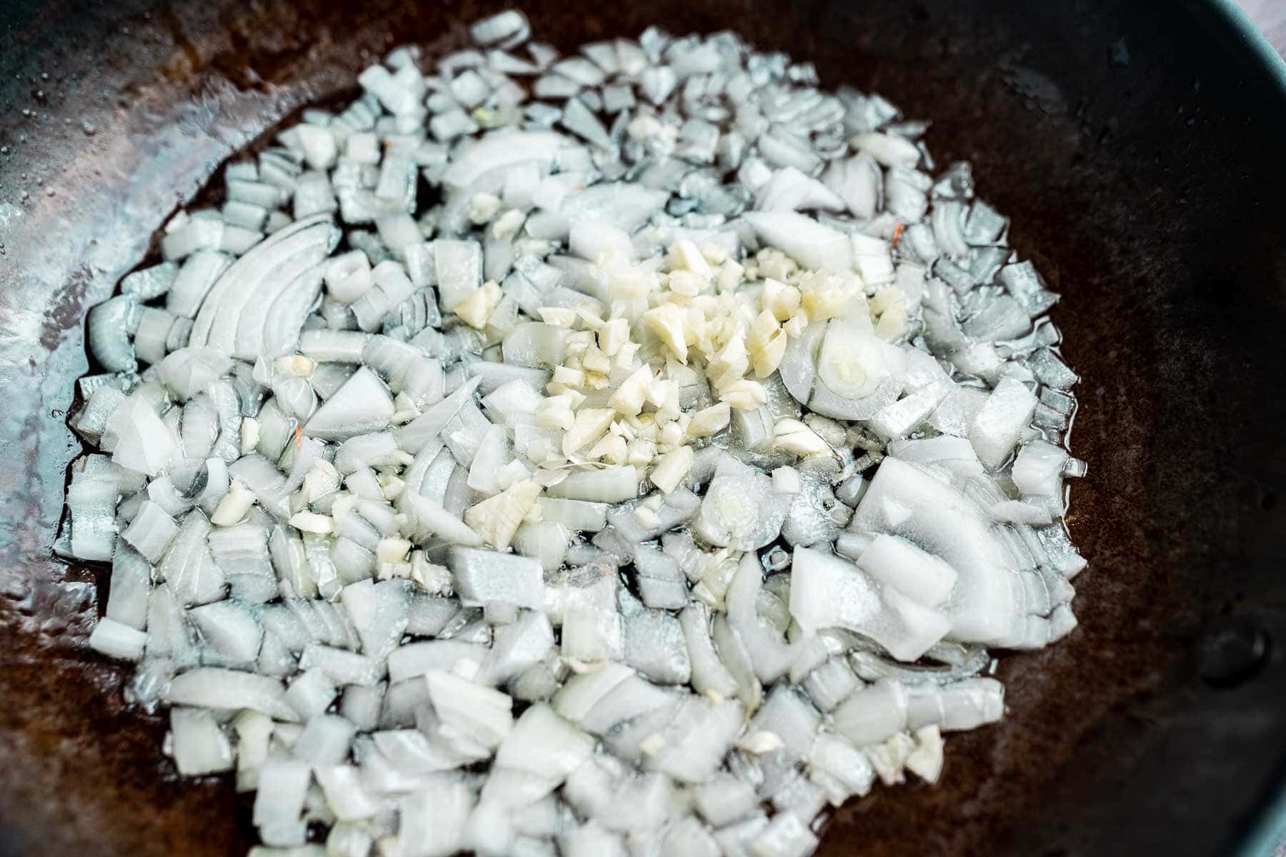 Chopped onions and garlic sautéing in a skillet.