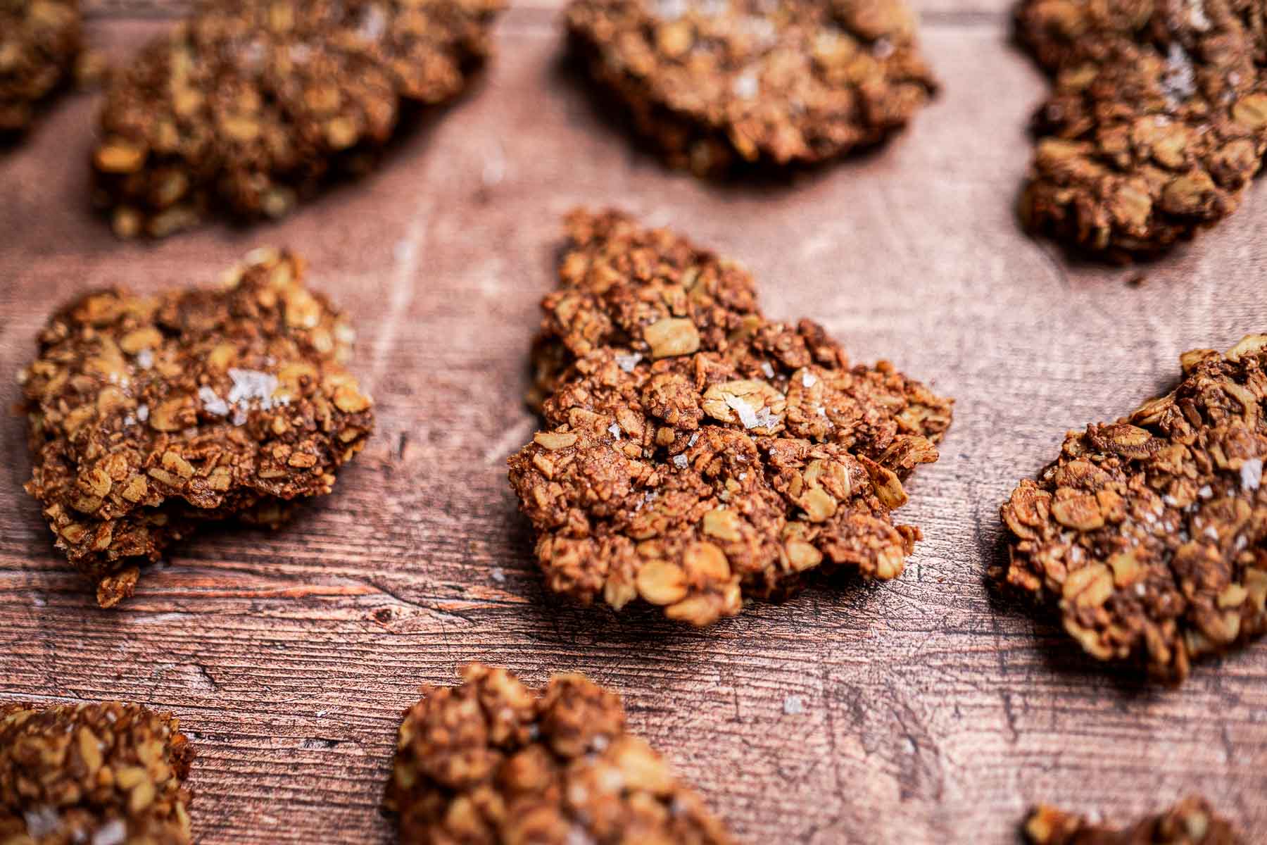 Close-up of brown oat and nut clusters arranged on a wooden surface.