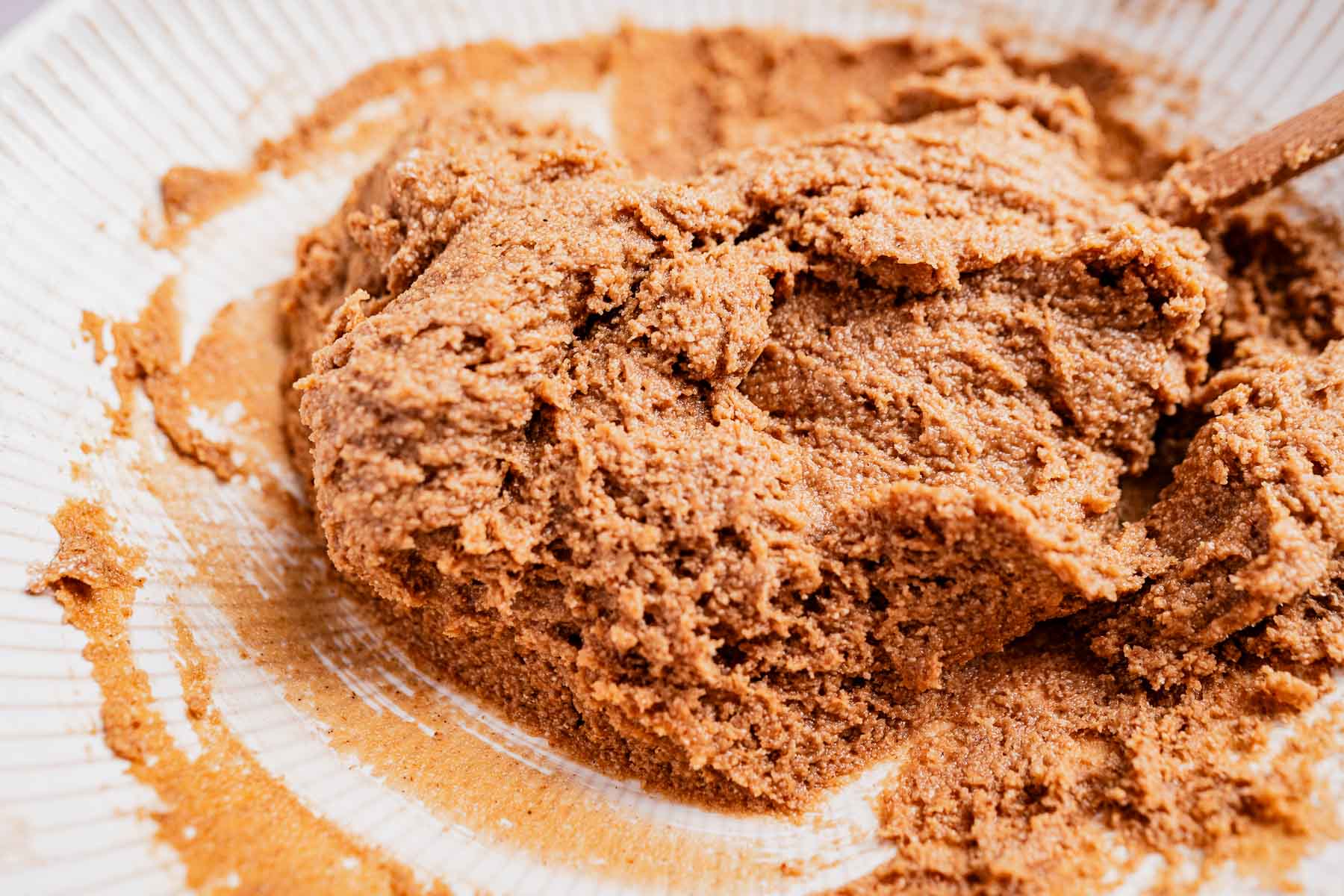 Close-up of brown sugar and butter mixture being stirred in a white mixing bowl, the perfect base for irresistible oat flour chocolate chip cookies.