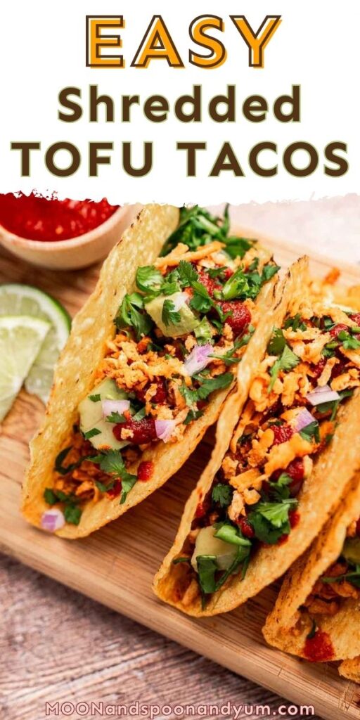 Tofu tacos are delicious. Two tantalizing tofu tacos with lettuce and salsa rest on a wooden board, garnished with chopped onions and herbs. Lime wedges and a bowl of salsa enhance the background's vibrant display.
