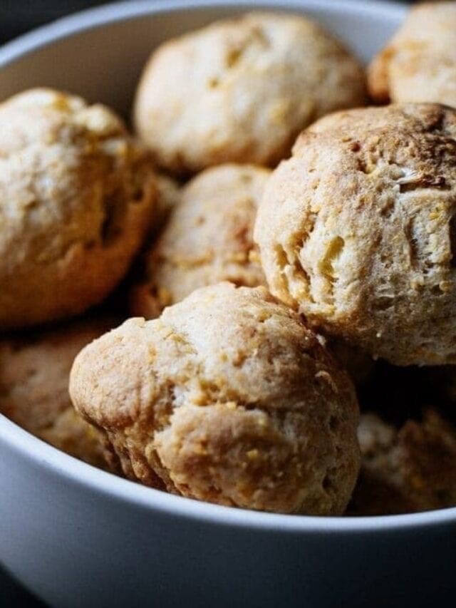 A white bowl filled with several golden-brown scones or biscuits.