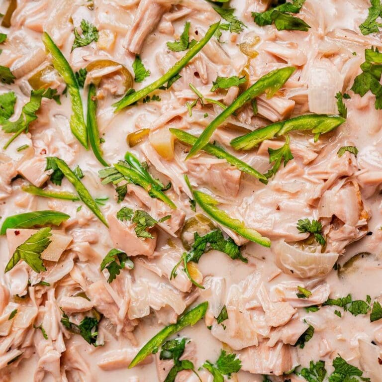 Shredded jackfruit in a creamy ginataang langka sauce, garnished with sliced green peppers, chopped onions, and fresh cilantro.