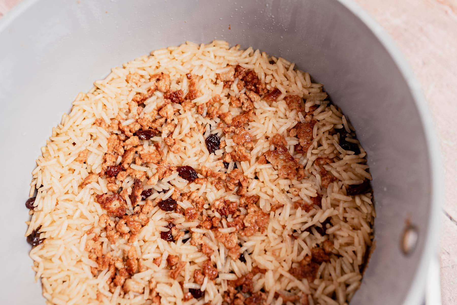 Cooked white rice with browned and slightly burnt bits at the bottom inside a pot, similar to the crispy layer found in Arroz con Coco.
