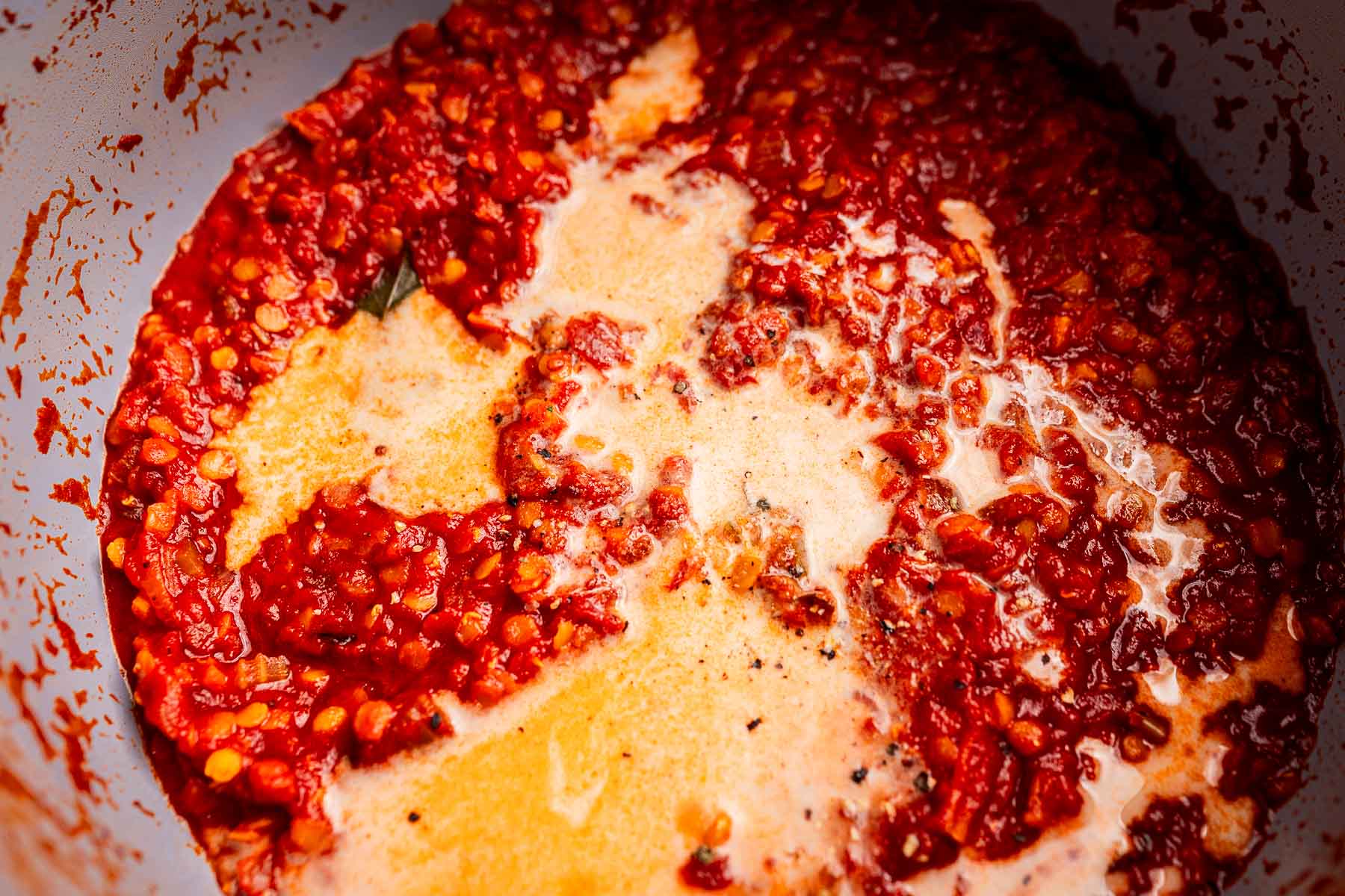 Red chili paste cooking in oil, with visible chunks of chili and a layer of oil separating from the mixture in a pan—perfect as a spicy base for vegetarian bolognese.