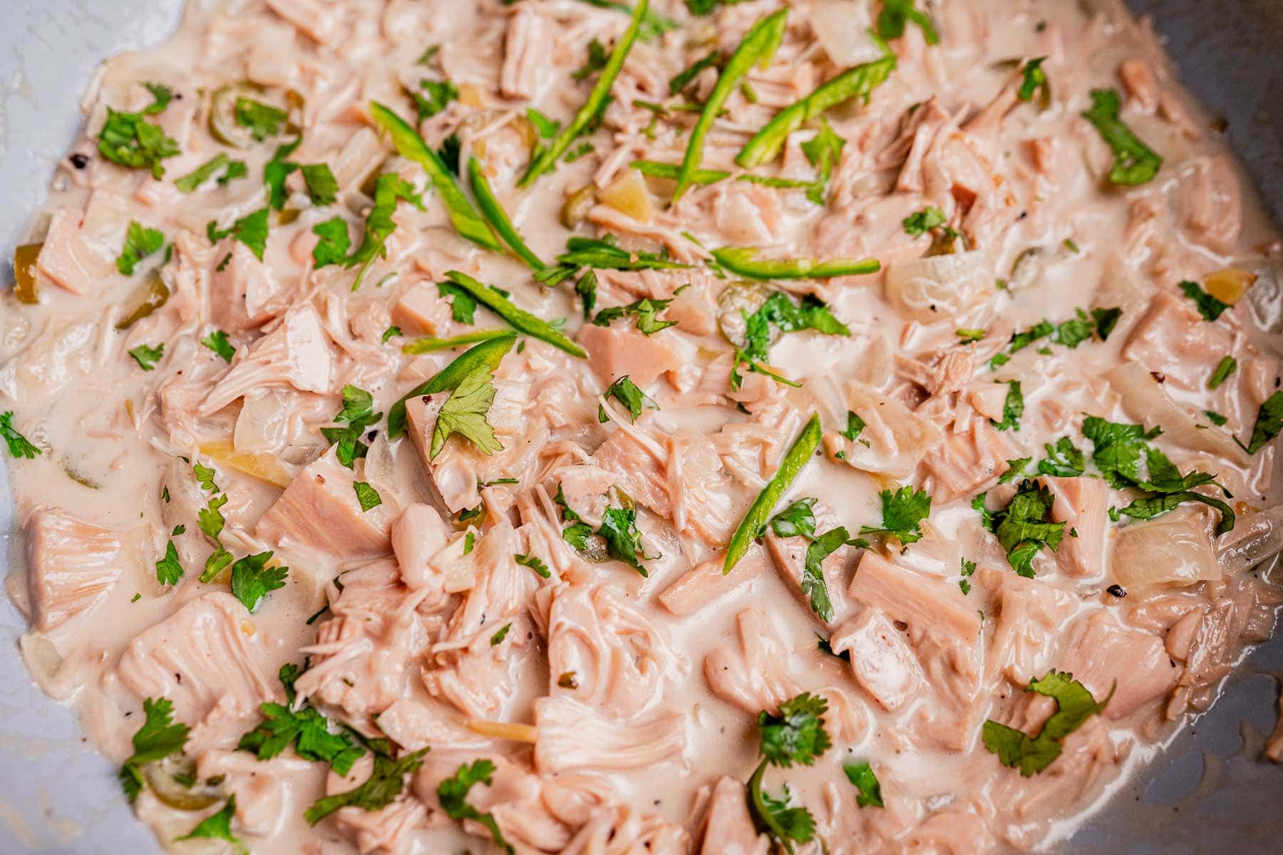 Shredded jackfruit cooked in a creamy ginataang langka sauce, garnished with chopped cilantro and sliced green chilies.
