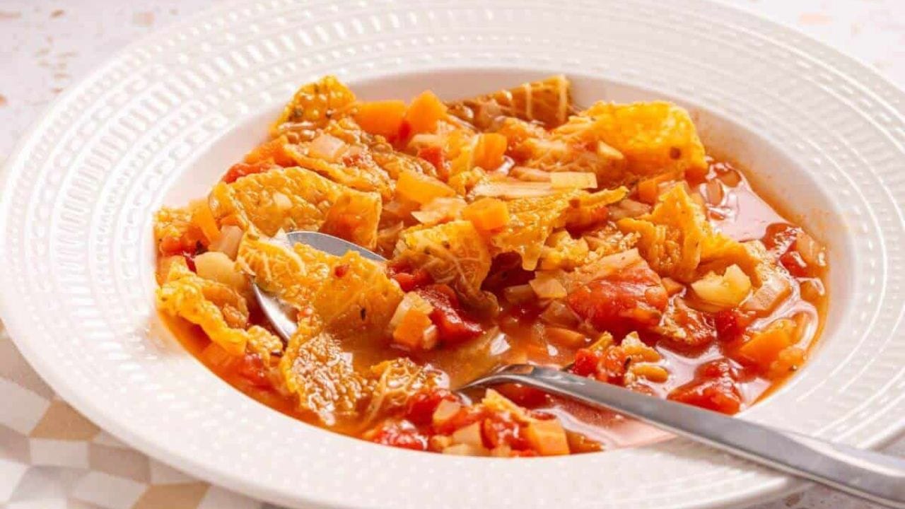 A bowl of hearty tomato-based soup with cabbage.