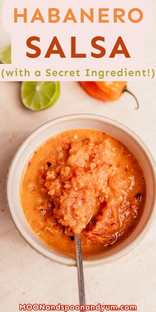 A bowl of spicy habanero salsa with a spoon sits on a beige surface, surrounded by a lime wedge and habanero pepper. Text reads “Habanero Salsa (with a Secret Ingredient!).”.