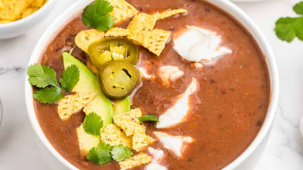 An image of slow cooker black bean soup in a bowl with toppings.