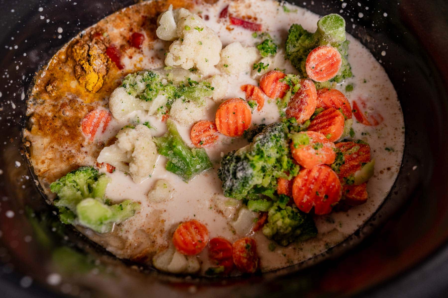 Frozen broccoli, cauliflower, and sliced carrots simmer in a creamy liquid with spices for an easy slow cooker vegetable curry.