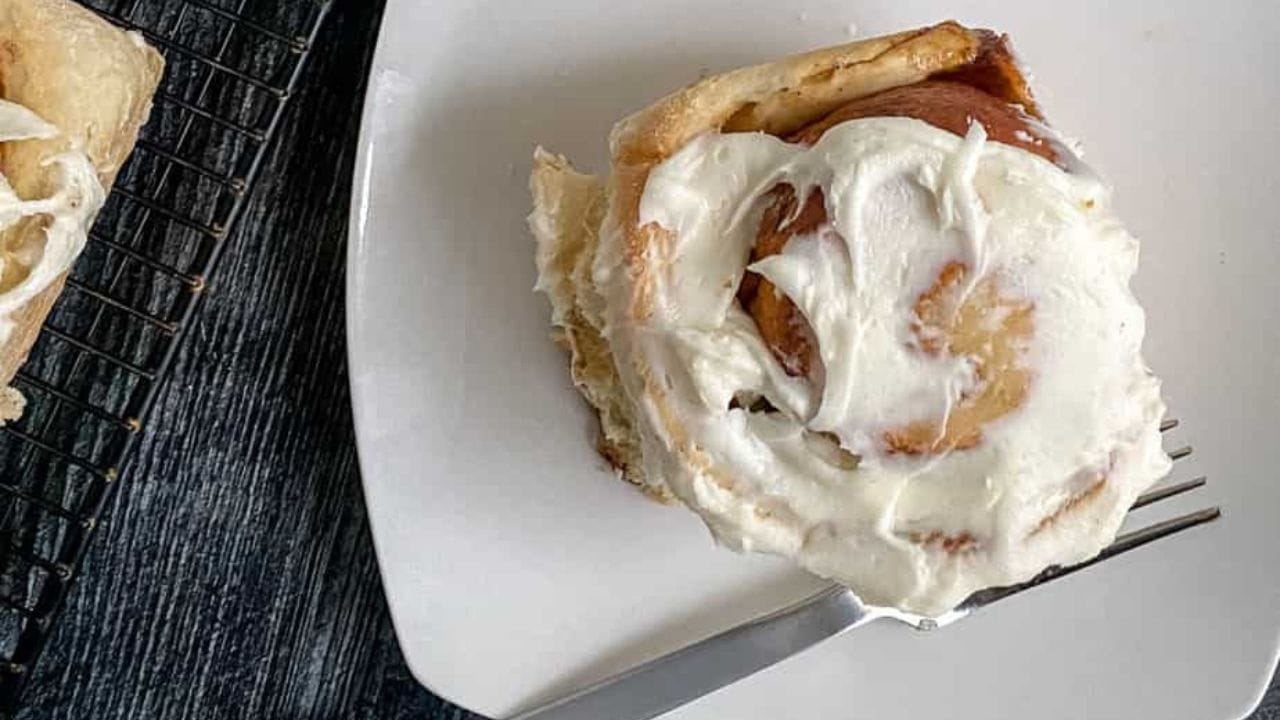 Gingerbread rolls with cream cheese frosting on a plate.