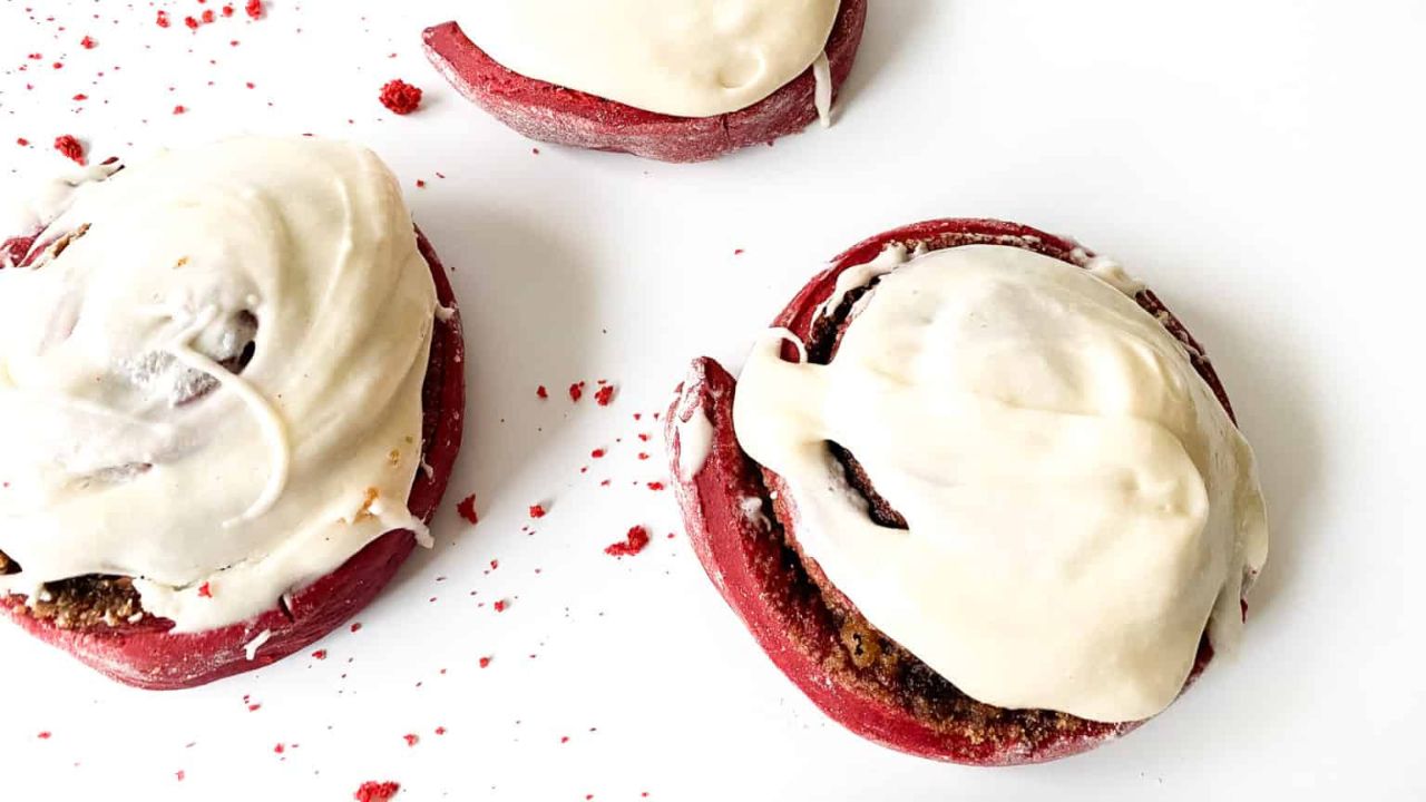 Red velvet cinnamon rolls top with smooth and creamy frosting.