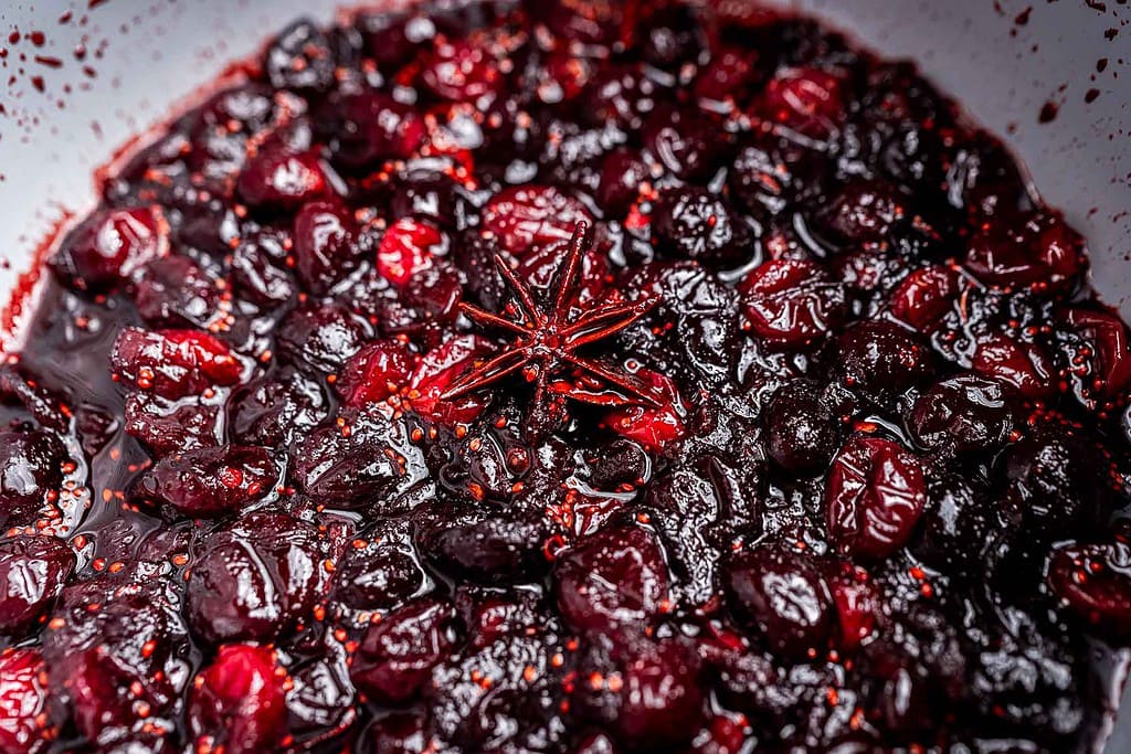 Close-up of cooked cranberries in sauce with a star anise pod in the center, perfect for making homemade cranberry chutney.