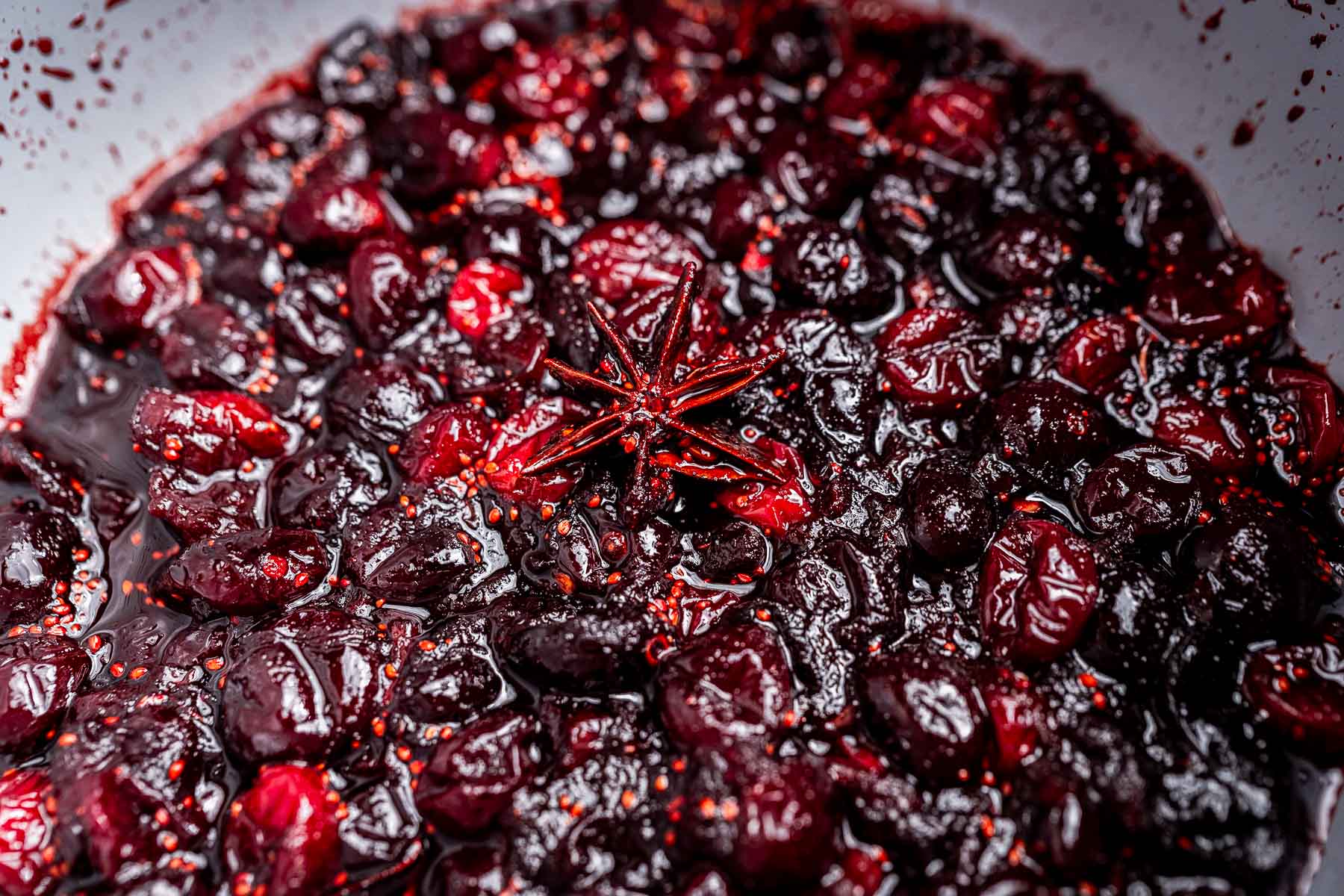 Close-up of cooked cranberries in sauce with a star anise pod in the center, perfect for making homemade cranberry chutney.