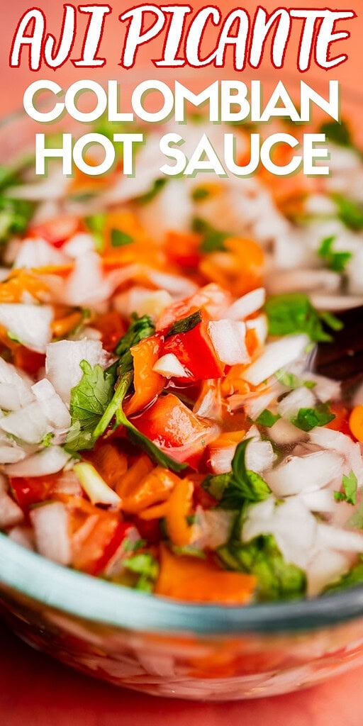 A close-up of aji picante Colombian hot sauce in a glass bowl, showing chopped onions, cilantro, and red peppers. Text reads "Aji Picante Colombian Hot Sauce.