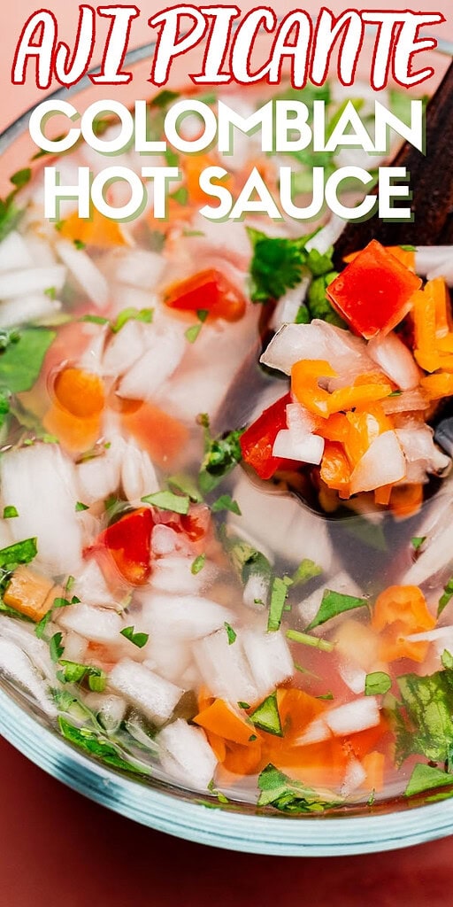 Close-up of a bowl of aji picante, the classic Colombian hot sauce, with chopped onions, tomatoes, cilantro, and peppers. Text on image reads "Aji Picante Colombian Hot Sauce.