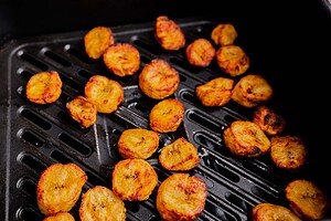 Air fryer sweet plantains are sliced and arranged in a single layer, then cooked until golden and caramelized in the air fryer basket.