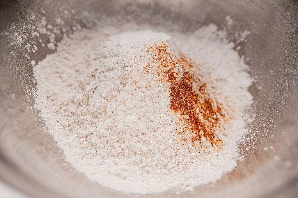 A metal bowl containing a pile of flour with a small amount of reddish-brown spice on top, perfect for making gluten free scones.