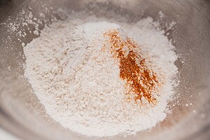 A metal bowl containing a pile of flour with a small amount of reddish-brown spice on top, perfect for making gluten free scones.