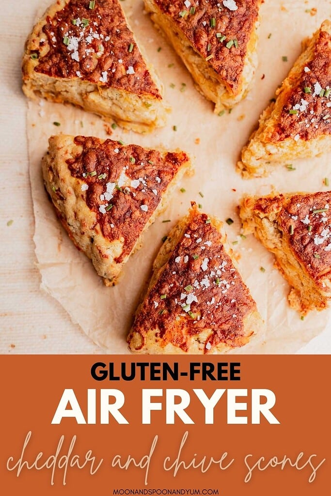 Six triangular gluten free scones with cheddar and chive, arranged in a circle on parchment paper, with text reading “Gluten-Free Air Fryer Cheddar and Chive Scones.”.