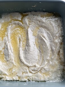Unbaked cake batter swirled with melted butter in a blue baking dish, reminiscent of gluten free butter swim biscuits.