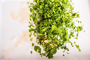 Chopped fresh greens and minced garlic on a white surface, with some liquid and seasonings visible—perfect ingredients for savory baked dumplings.