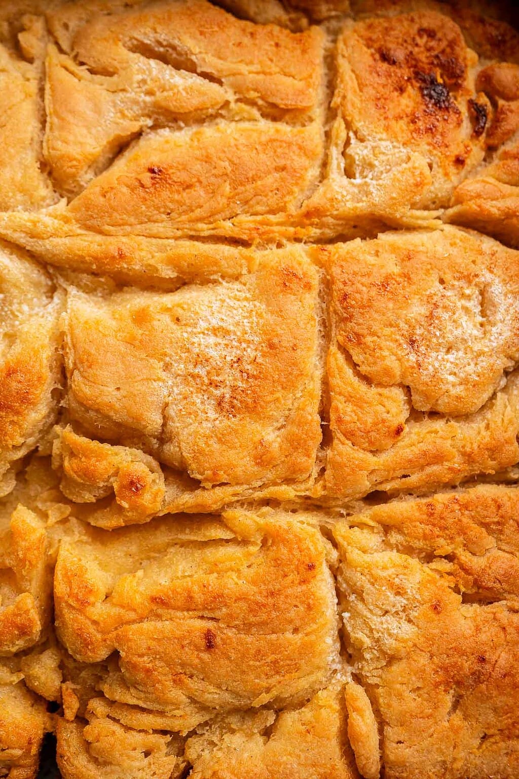 Close-up view of golden brown, flaky layers of gluten free butter swim biscuits, showing a textured and slightly crispy surface.