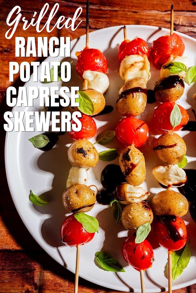 A plate of grilled skewers with cherry tomatoes, small potatoes, mozzarella, fresh basil, and balsamic glaze, labeled "Grilled Ranch Potato Caprese Skewers.