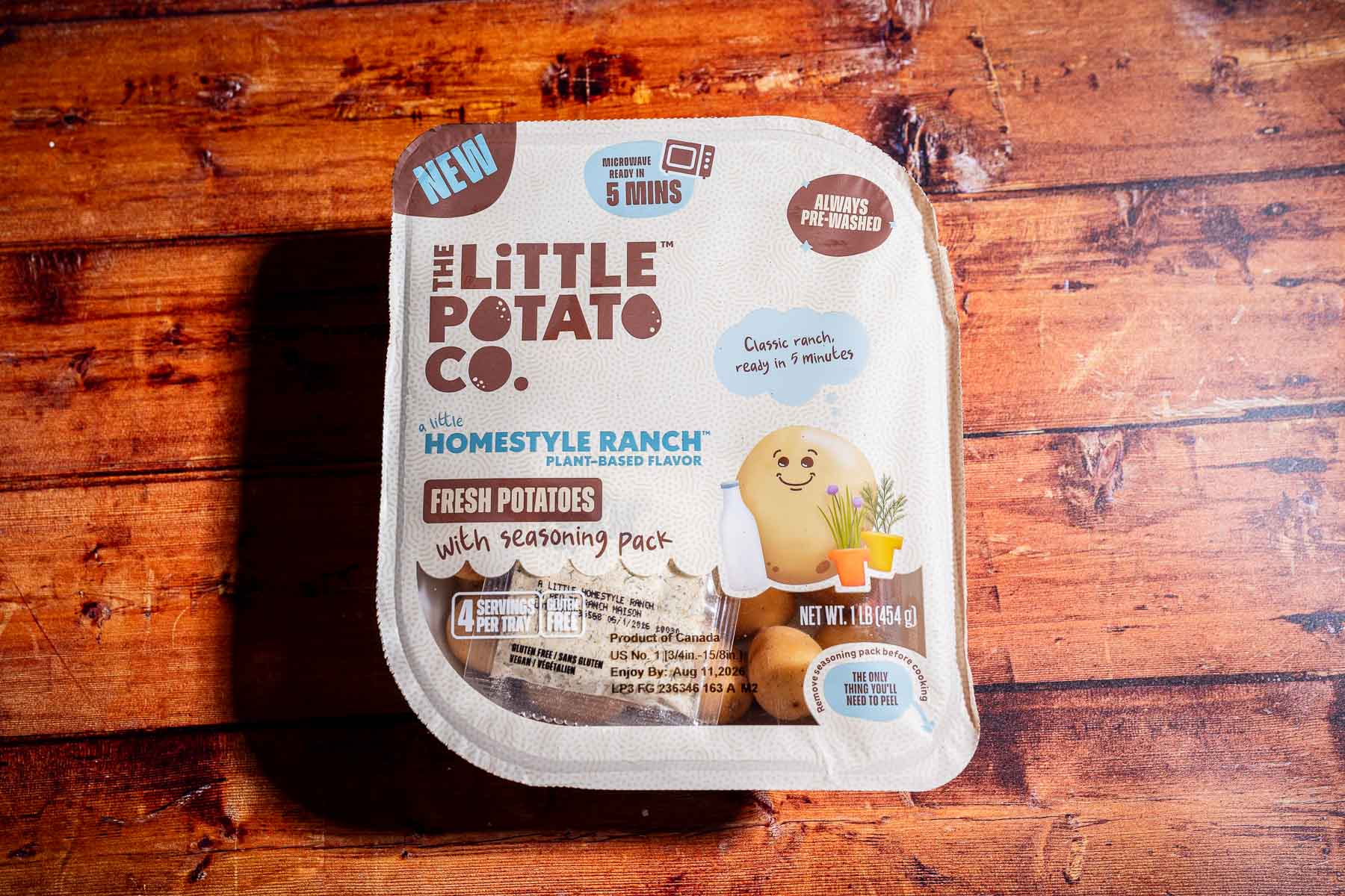 A container of The Little Potato Co. Homestyle Ranch fresh potatoes with seasoning pack on a wooden surface—perfect for quick 5-minute meals or pairing with caprese skewers for a delicious, plant-based flavor.