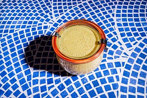 A glass jar with an orange rubber seal and metal clasps, perfect for storing cabbage salad, sits on a blue and white mosaic tile surface.