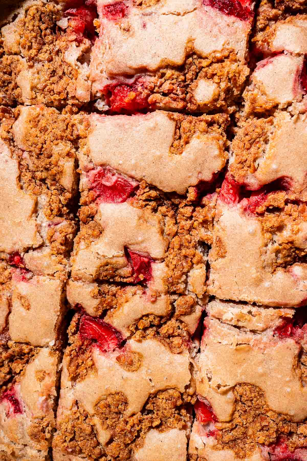 Close-up of sliced strawberry buckwheat cake bars, showing a golden crumb topping and visible pieces of strawberry.