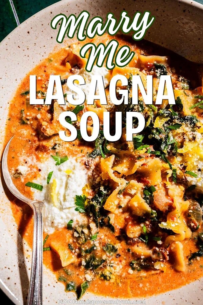 A bowl of marry me lasagna soup with pasta, ground meat, tomato broth, ricotta cheese, herbs, and a spoon, topped with grated cheese and parsley. Text overlay reads "Marry Me Lasagna Soup.