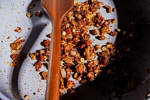 Chopped onions, garlic, and spices sautéing in a gray pan with a wooden spoon as the base for a flavorful purple sweet potato curry.