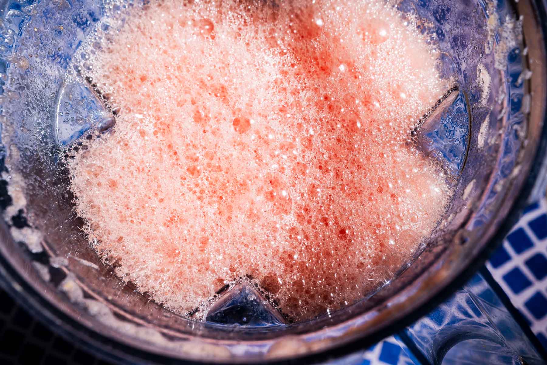 Top-down view of a blender containing a frothy pink liquid mixture, suggesting that ingredients for watermelon agua fresca have just been blended.