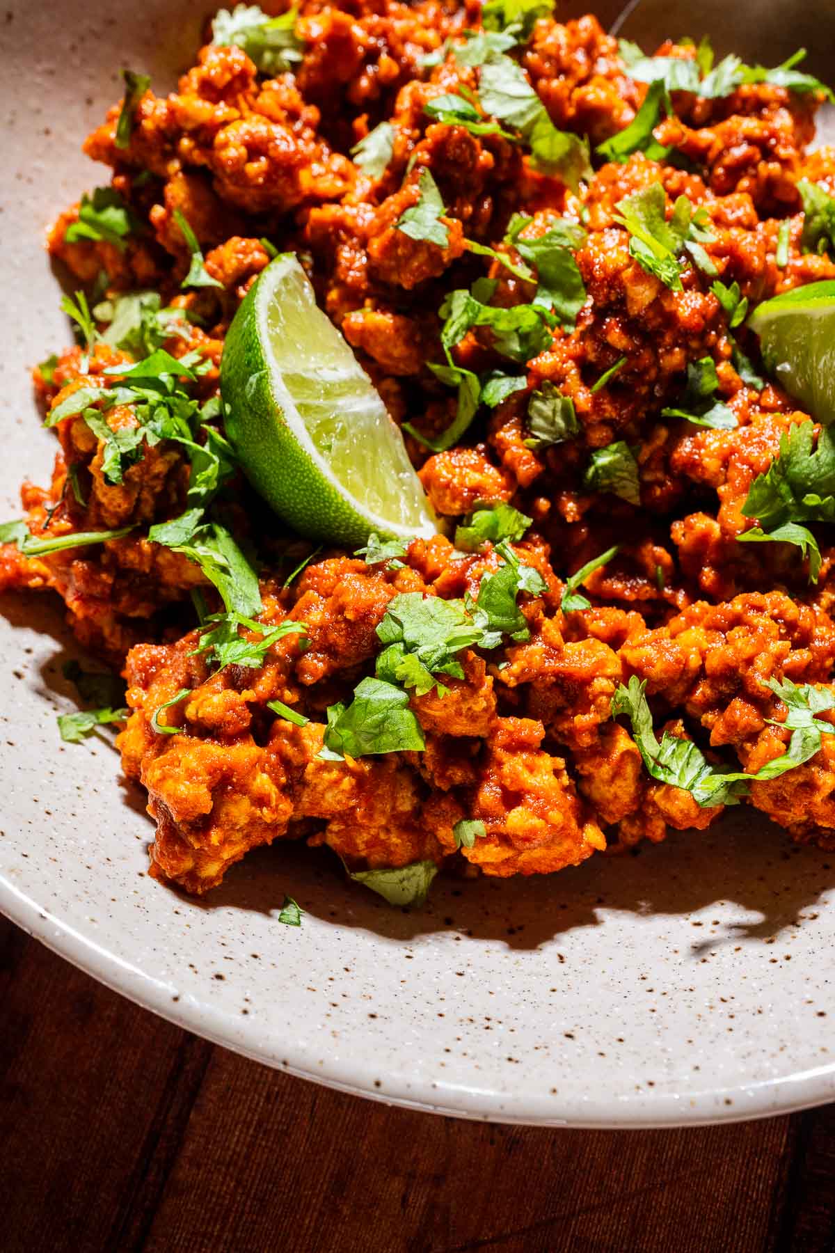 A plate of crispy tofu sofritas topped with chopped cilantro and served with lime wedges.