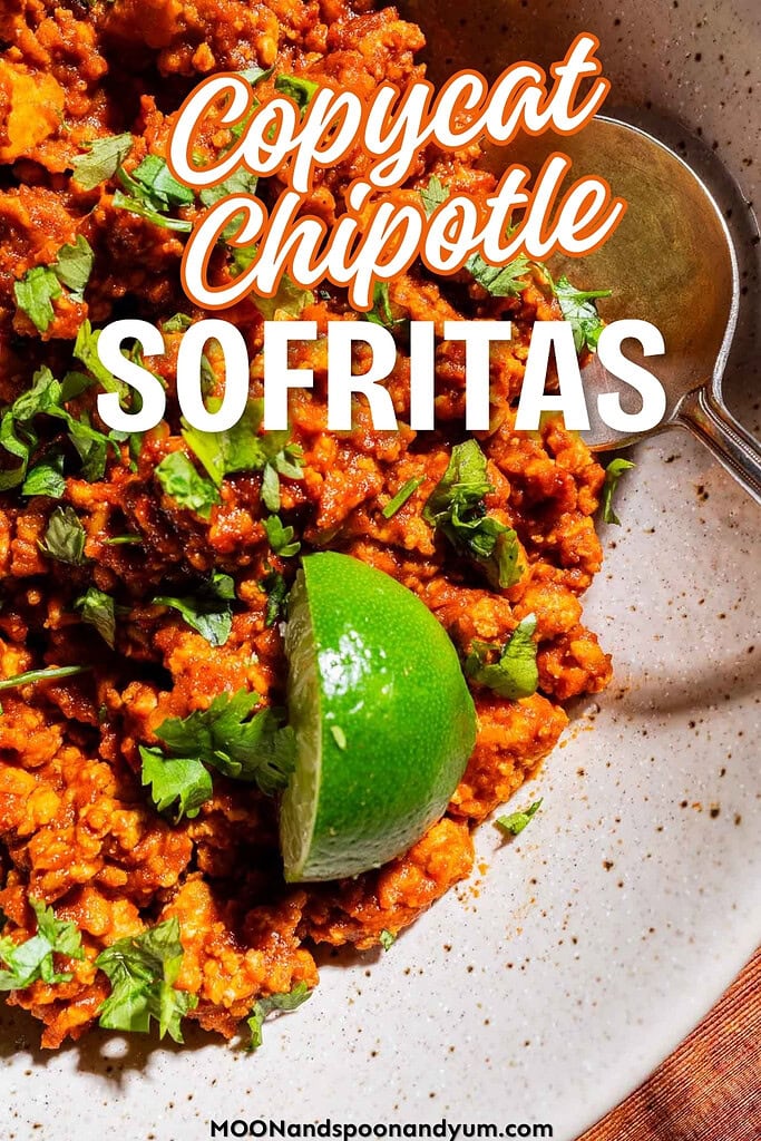 A bowl of sofritas garnished with chopped cilantro and a lime wedge, with a spoon on the side. Text overlay reads "Copycat Chipotle Sofritas.