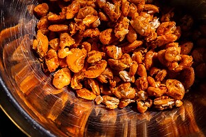 Close-up of a metal bowl filled with roasted, seasoned yellow split peas or lentils, some broken into pieces.
