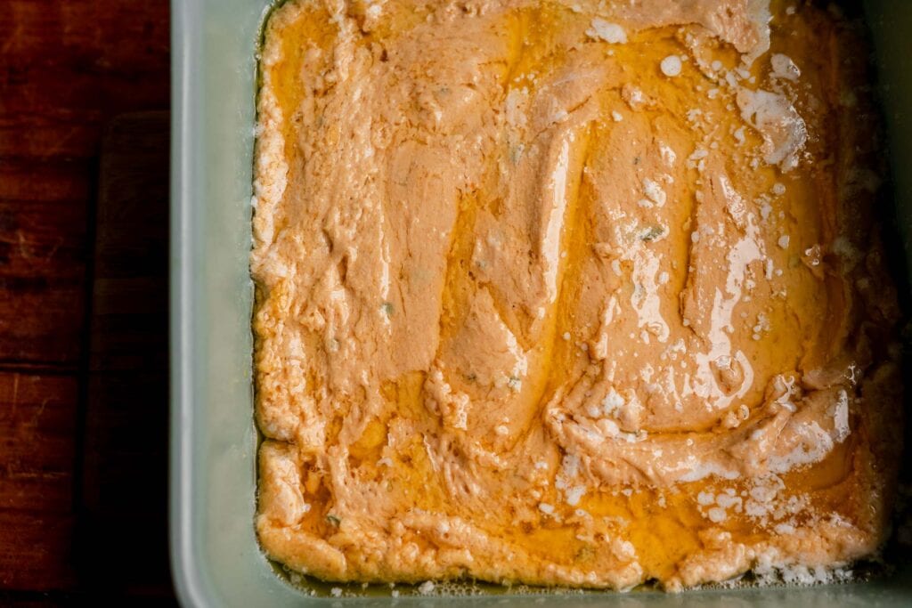 Pumpkin butter dip biscuit batter in a square baking dish, served alongside pumpkin butter swim biscuits.
